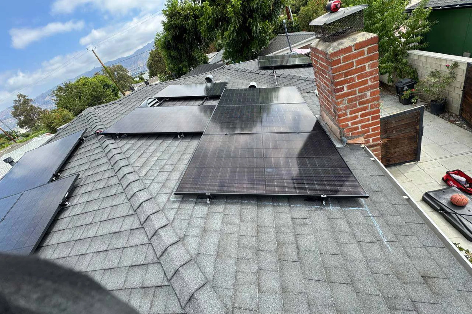 Solar array around a brick chimney on a shingle roof