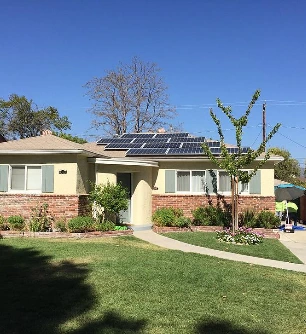 Cream stucco home with a new asphalt shingle roof and solar panels