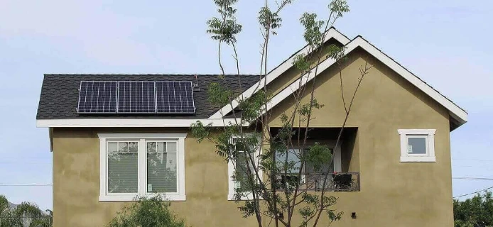 Two-story olive stucco home with a new dark shingle roof and reinstalled solar panels