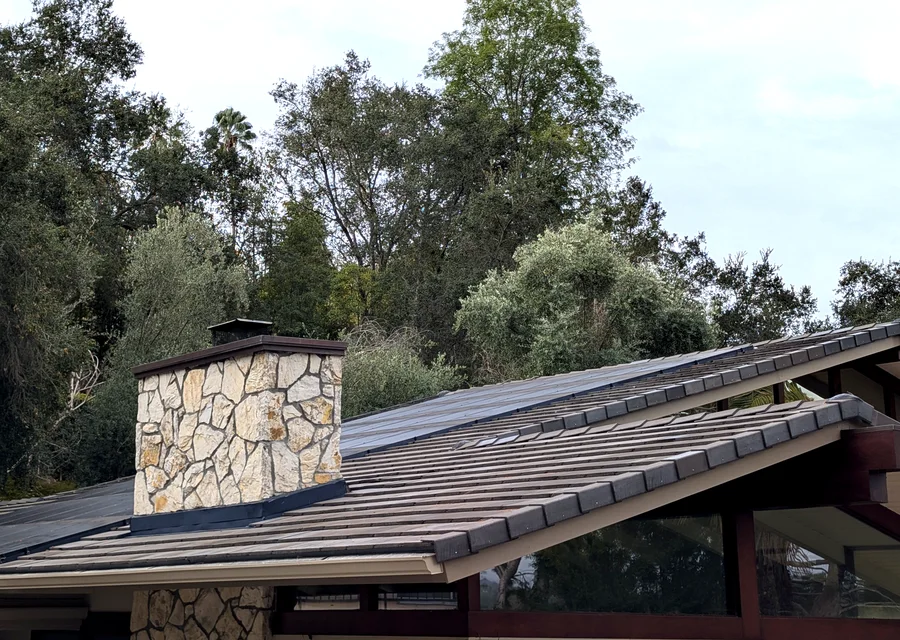 Solar panels back on the new concrete tile roof beside the stone chimney