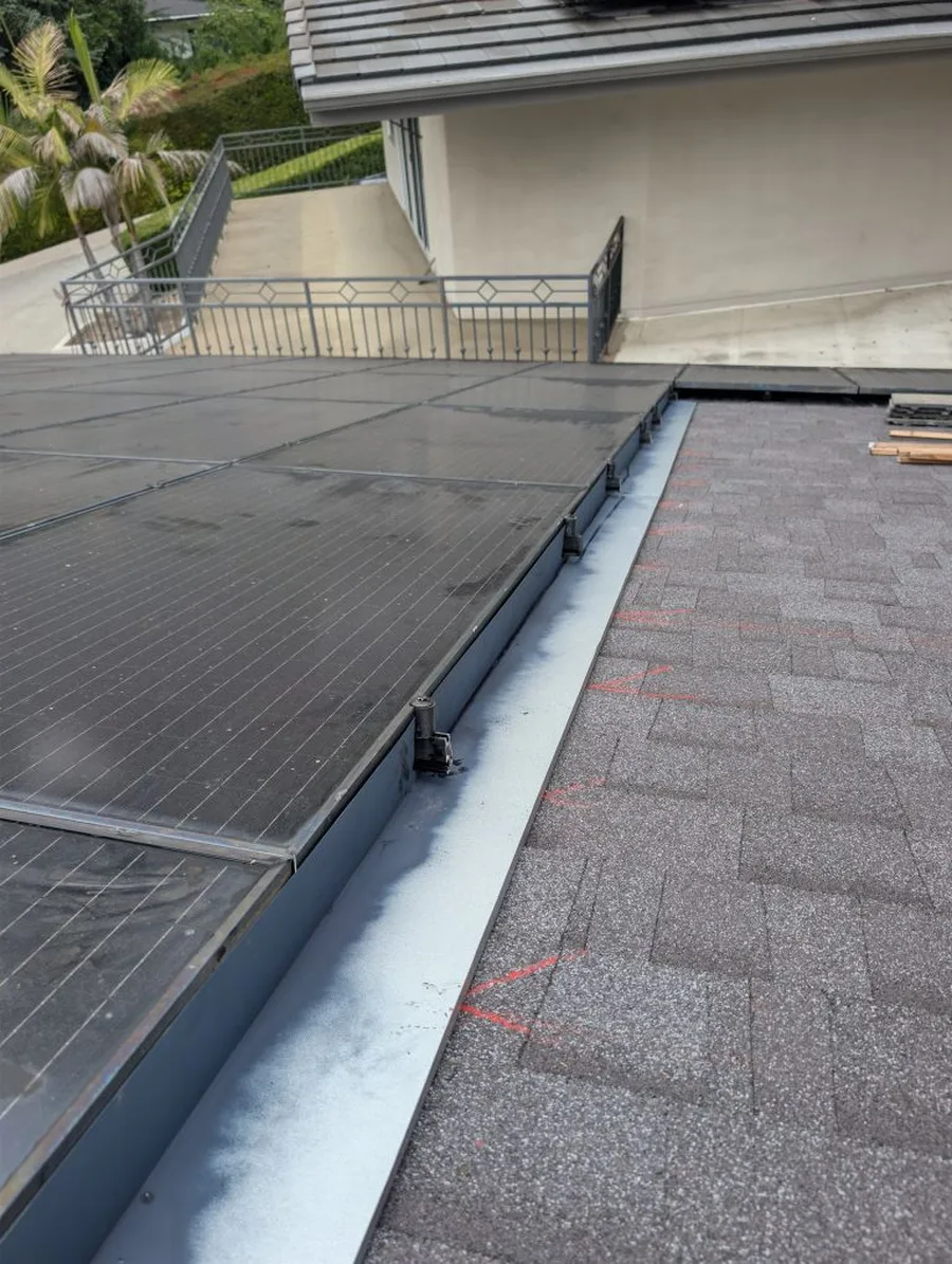 Side view of a finished RRR job: solar panels sitting low and flush, with metal edge flashing and the roof reset tight around the array