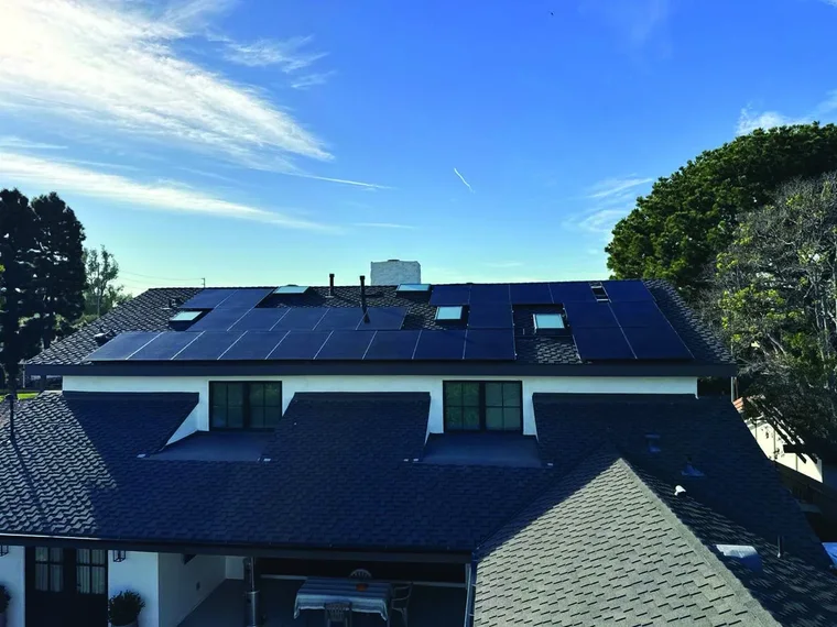 Two-story home with a dark shingle roof and black solar panels, a Green Conception roof and solar job